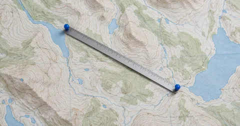 Illustration of a ruler connecting two blue markers on a contour map.