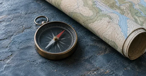 Illustration of an analog compass beside a rolled contour map on blue slate.